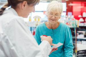 Senior woman in pharmacy talking to the chemist or pharmacist ex