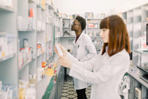 Two Young Multiethnical Pharmacists Working At Modern Pharmacy.