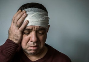 Injured-man-with-bandage-holding-his-head