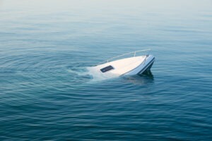 A boat sinks in blue water as a result of a capsizing accident. Contact a lawyer now.