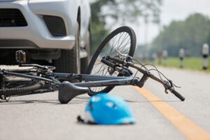 A bicycle lying in the road in front of a car.