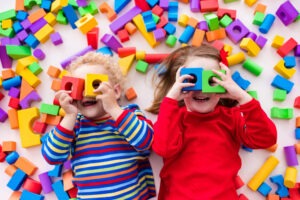 Kids cover their face with play blocks