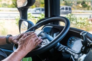 Senior truck driver’s hands texting on a mobile phone while driving. How does distracted driving impact truck accident cases?