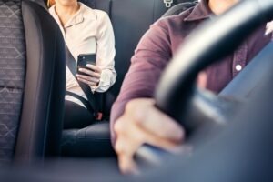 Person in a rideshare vehicle wondering, “Who pays for my injuries after a rideshare accident?”